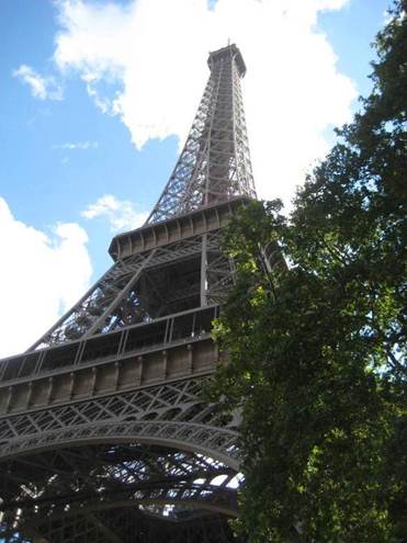 Schräger Blick auf den Eiffelturm von unten, mit Baum am rechten Rand